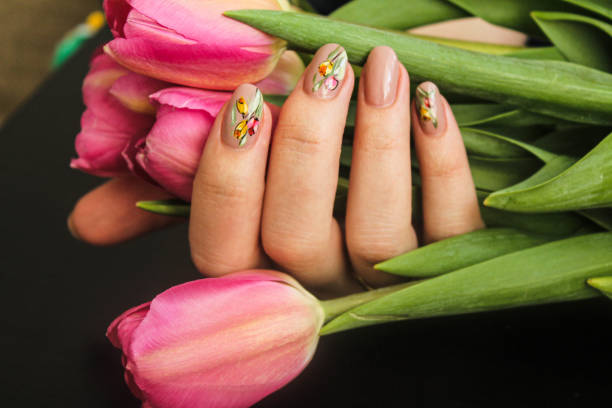 manicura de flores dibujado en las manos de las mujeres sosteniendo un ramo de flores - fingernail manicure beauty decoration fotografías e imágenes de stock