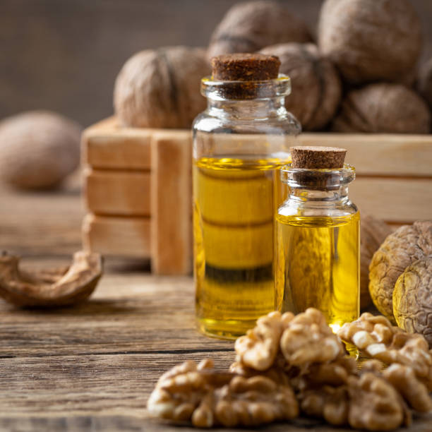 istock Glass bottle with walnut oil and walnut kernel on a wooden table. 1215098074
