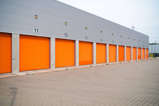 istock warehouses with orange roller doors 1215098578