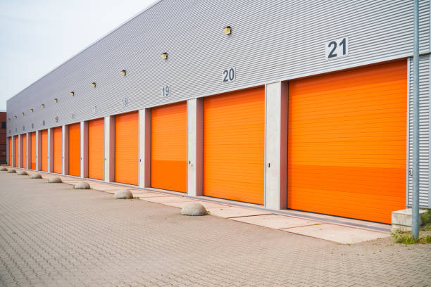 istock warehouses with orange roller doors 1215098627