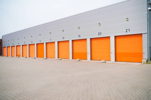 istock warehouses with orange roller doors 1215099751
