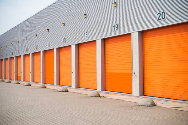 istock warehouses with orange roller doors 1215099772