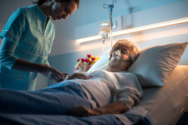 Nurse checking a senior patient at the hospital Professional nurse checking a senior woman lying in bed at the hospital night hospital bed stock pictures, royalty-free photos & images
