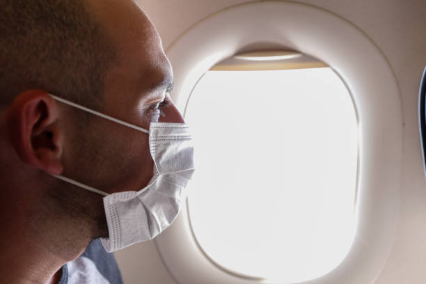 verticale croppede de l’homme dans le masque de respirateur volant sur un avion. - color image people air vehicle airplane photos et images de collection
