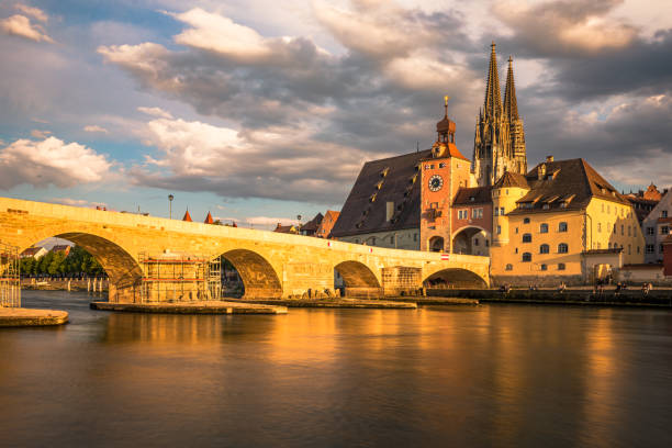 istock Historical Stone Bridge and Bridge tower with the iconic Cathedral as a background in Regensburg, Germany - Creative Stock Image 1215110224