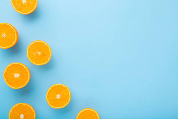 istock Bright halves of oranges. Fresh fruits. Empty place for text on light blue table background. Pastel color. Closeup. Top down view. 1215110894