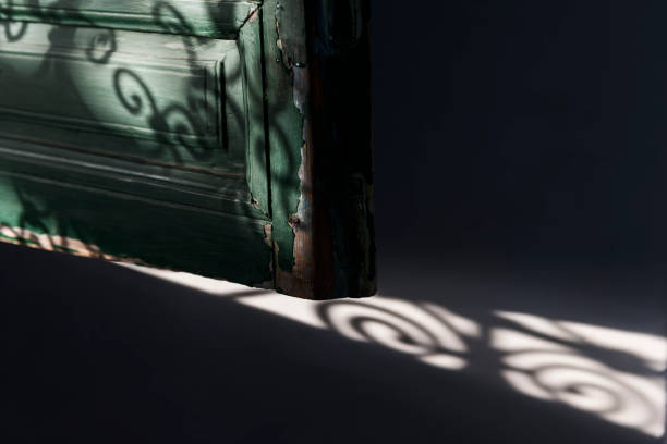 istock Old wooden window shutter (blind) detail with Moroccan window grid shadows. 1215112242