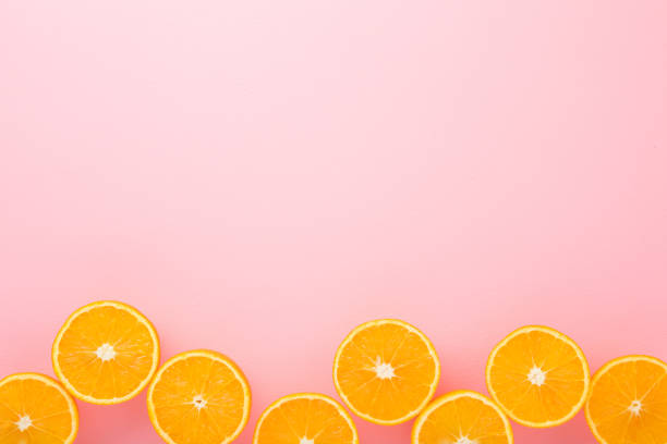 istock Bright halves of oranges. Fresh fruits. Empty place for text on light pink table background. Pastel color. Closeup. Top down view. 1215112353