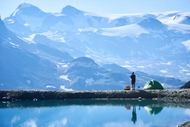 istock Man using radio near tent in mountains. 1215113225