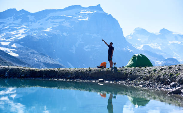 istock Male hiker standing by camp tent in mountains. 1215113248