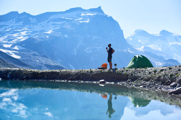 istock Man using radio near tent in mountains. 1215113272