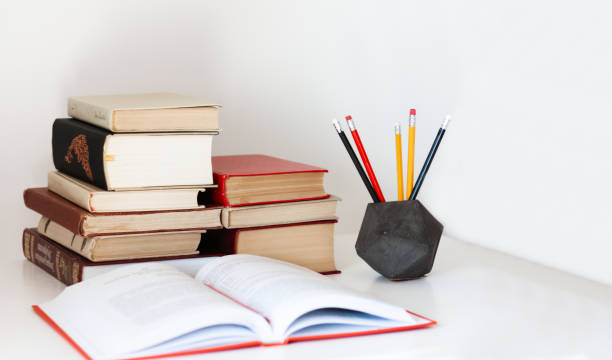 istock Home office: textbook, notebook, stack of old books retro education back to school background, pencils in holder with copy space for text 1215114891