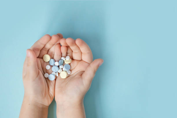 istock blue, white and yellow tablets in the palms on a blue background 1215114923