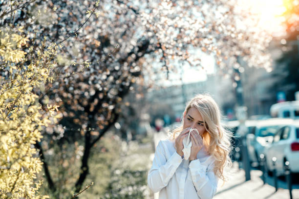 чихание женщины в цветущей огороде - allergy pollen tree hay fever стоковые фото и изображения