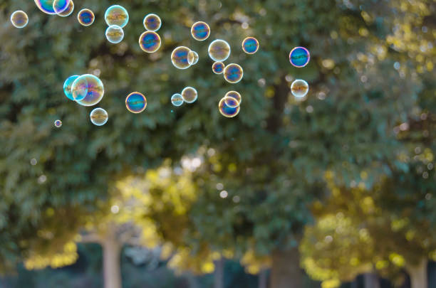 istock Soap bubbles floating against green trees 1215117676