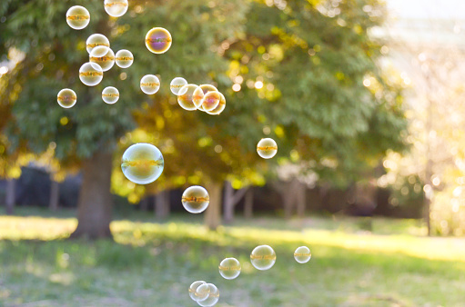Young mother and daughter having fun in park with Soap Bubbles