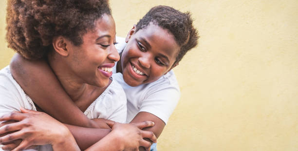 felice giovane madre che si diverte con suo figlio - figlio che abbraccia sua madre all'aperto - connessione familiare, maternità, amore e concetto di momenti teneri - concentrati sul viso del ragazzo - child caribbean black latin american and hispanic ethnicity foto e immagini stock