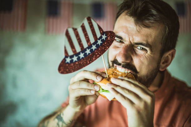 istock Young happy man eating burger on Independence day. 1215121037