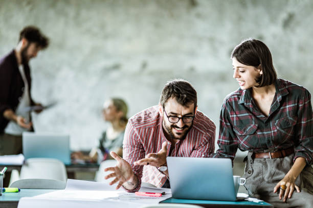 istock Design professionals cooperating while working on laptop at casual office. 1215121199