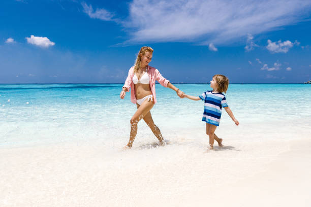istock Happy single mother and her small boy walking through sea on the beach. 1215123715