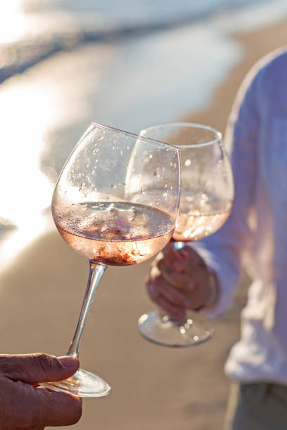 couple  holding rose wine glasses  at the  beach - rose rosé women valentines day imagens e fotografias de stock