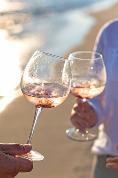 couple  holding rose wine glasses  at the  beach - rose rosé women valentines day imagens e fotografias de stock