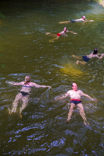Tourists enjoying swimming in cool, refreshing water coming out from Clear Water Caves, Borneo Malaysia.