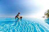 Happy little boy having fun with his mother during summer day in the pool.