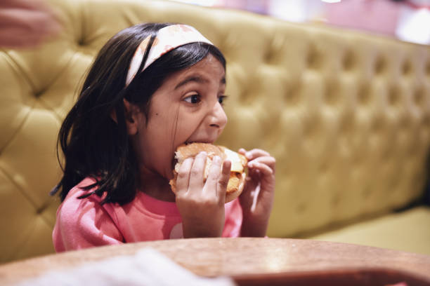 istock Girl (6-7 years) eating burger 1215125618