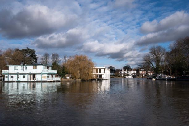 Houseboat living and mooring on River Thames Floating houseboats moored along the shore of the River Thames near Molesey and Hampton Court in the United Kingdom hampton court stock pictures, royalty-free photos & images