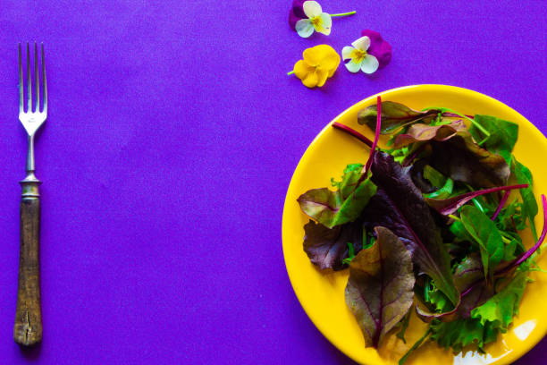 Mix salad leaves on a plate, stone or purple background.