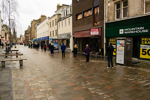 People queuing for Pharmacy in Perth with closed stores. In the Rain. In Perth Scotland