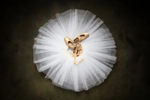 Professional ballet shoes with ribbons on a white tutu in a dance studio