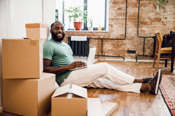 istock Joyful man with boxes and laptop stock photo 1215132480