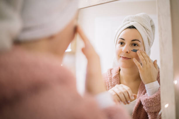 istock Mirror reflection of a girl applying mud mask on her face 1215132540