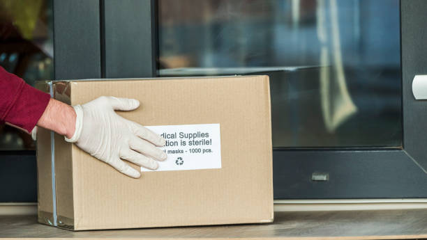 Courier brings a box with protective medical masks to the doorstep stock photo