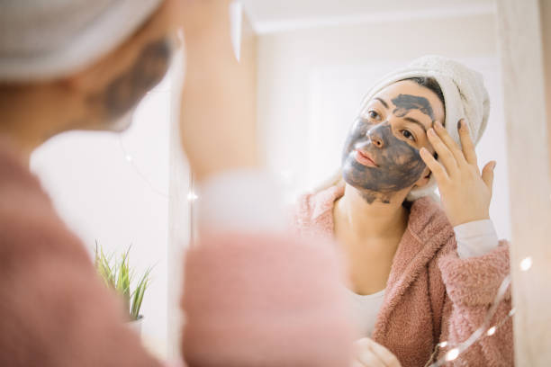 istock Lady applying charcoal mask on her face 1215132682