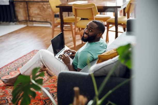 istock Positive barefooted man with gadget stock photo 1215132755