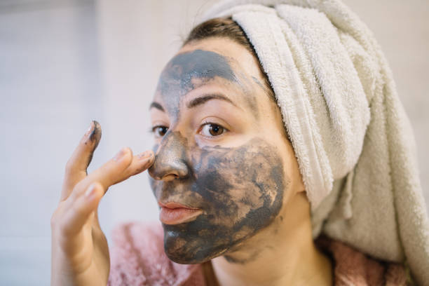 istock Young girl with charcoal mask touching her nose 1215132767