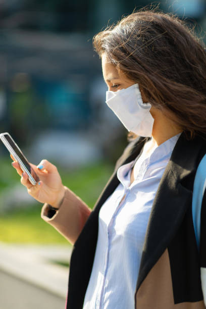 istock Woman with protective face mask looking at smart phone 1215136001