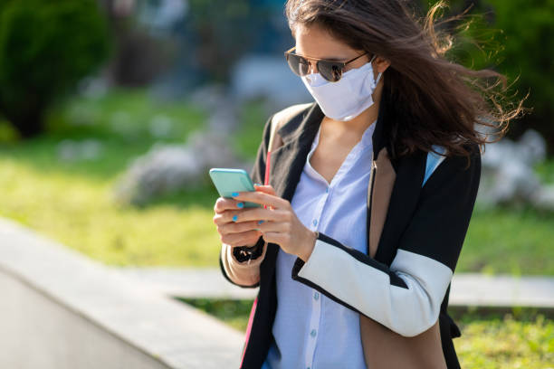 istock Woman with protective face mask texting on mobile phone 1215136044