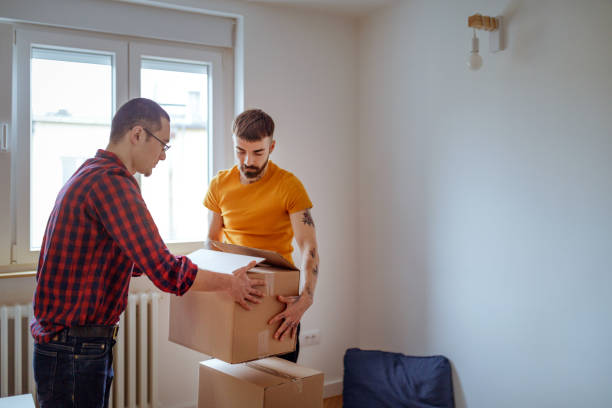 istock Gay couple stacking boxes in the empty living room 1215138034