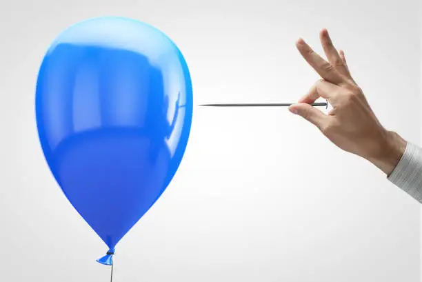 Photo of Blue balloon and needle in hand.