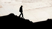 Shadow silhouette of a man walking alone down city stairs