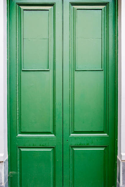 A green and old entrance door to a building.