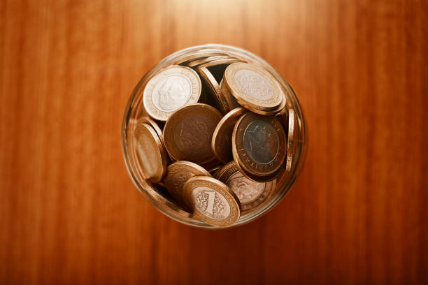 istock Coin savings jar full with cash on a table from directly above 1215141472