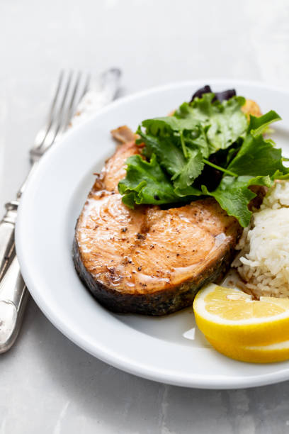 istock fried salmon with boiled rice, salad and lemon on white plate 1215144984