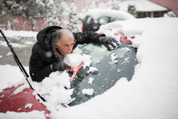 istock Man clears snow from windshield of car 1215146644