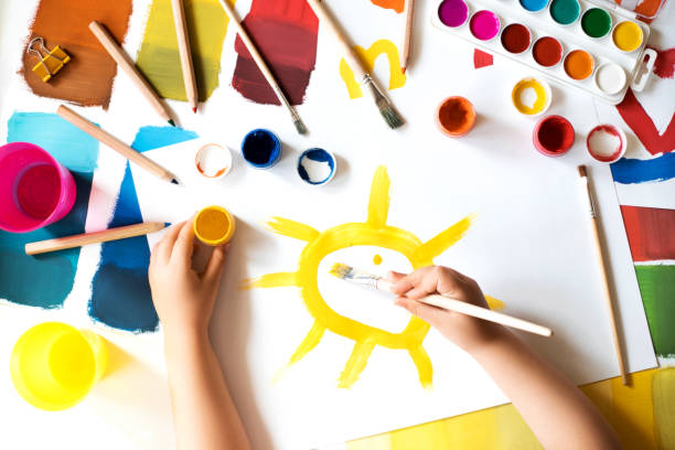 Close up of child's hands drawing at white paper. Close up of child's hands drawing sun at white paper by gouache. corona sun photos stock pictures, royalty-free photos & images