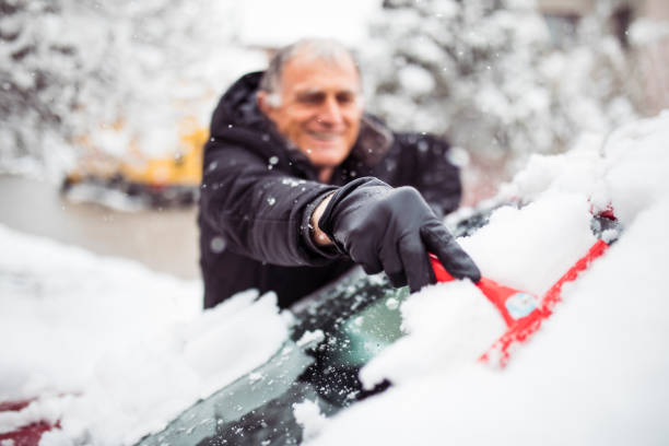 istock Man cleaning snow off his car 1215146652